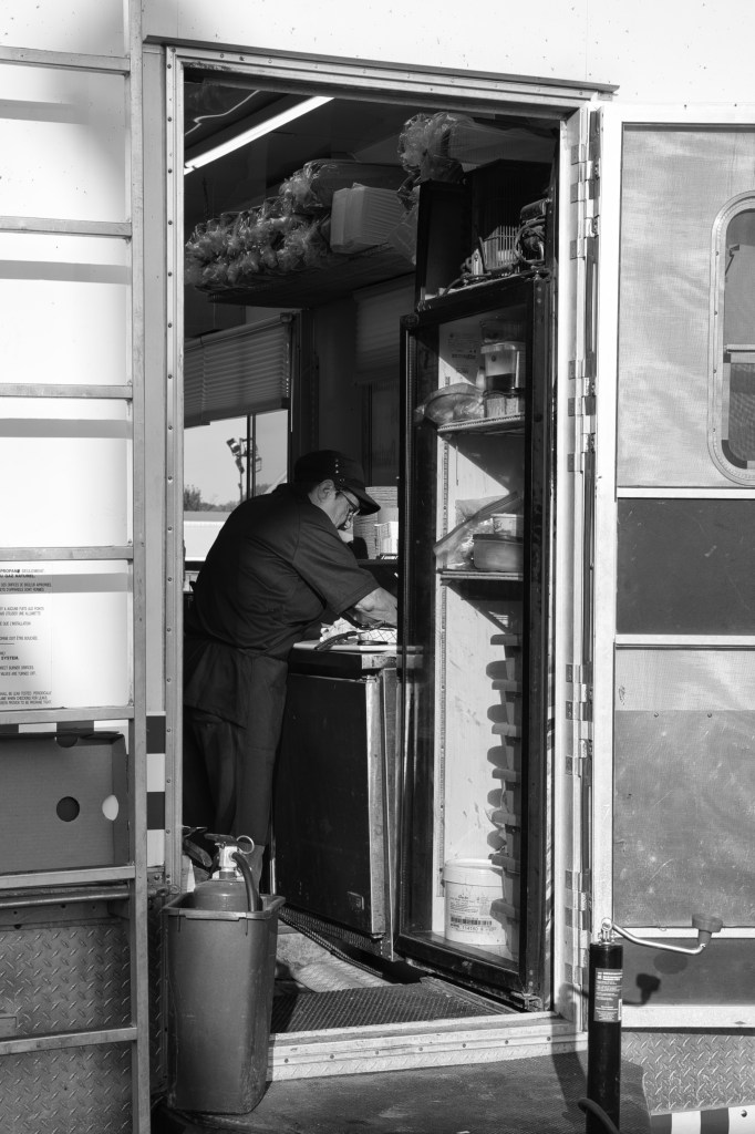 a woman seen through a trailer doorway washes dishes at a fair food booth