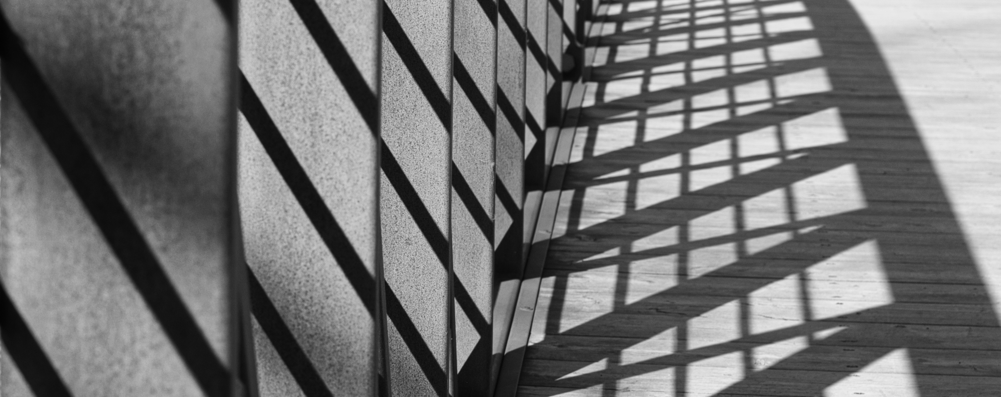 shadows from a bridge railing on the wooden floor of the bridge