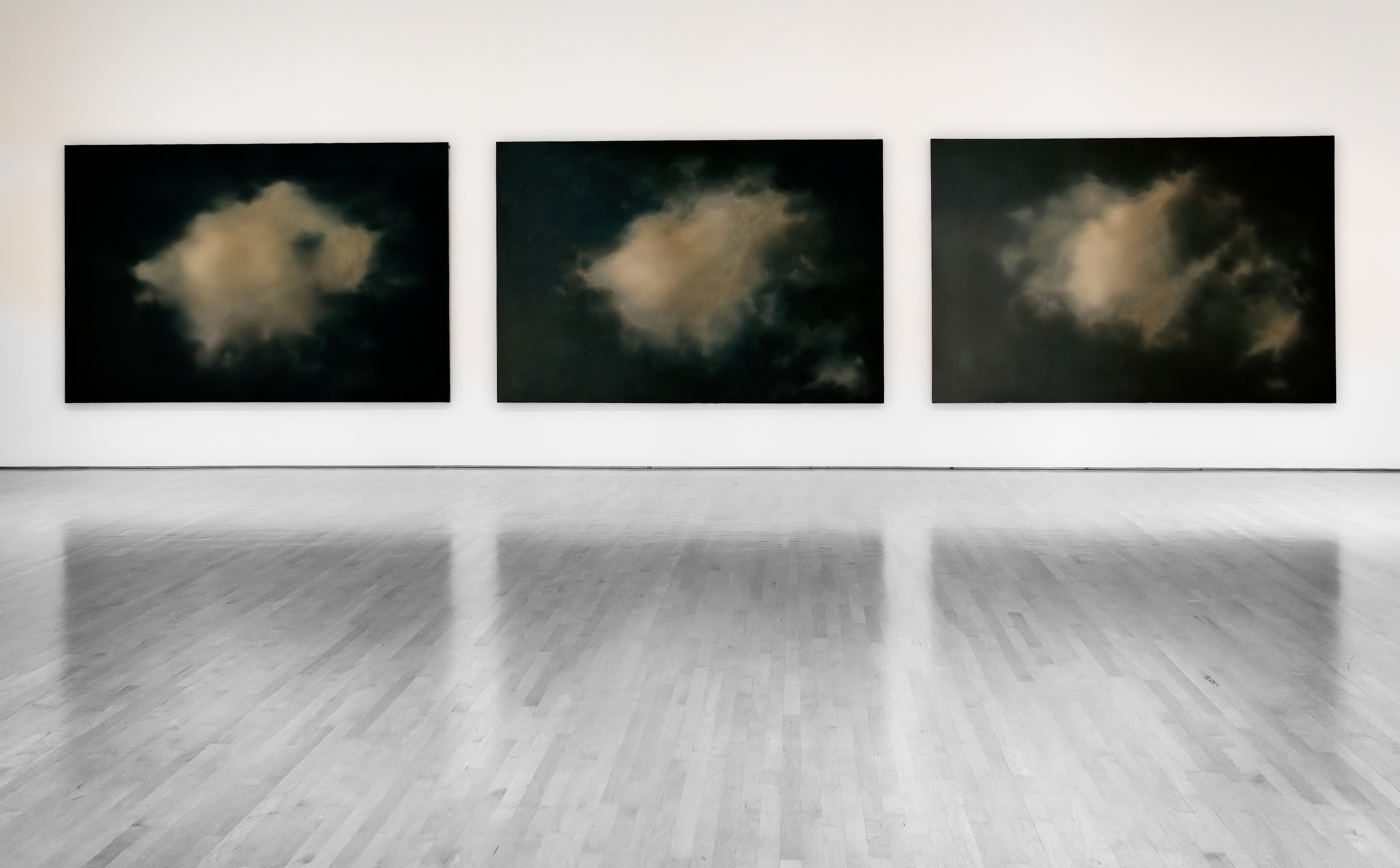 three colour paintings of cloudy images grace a black and white background