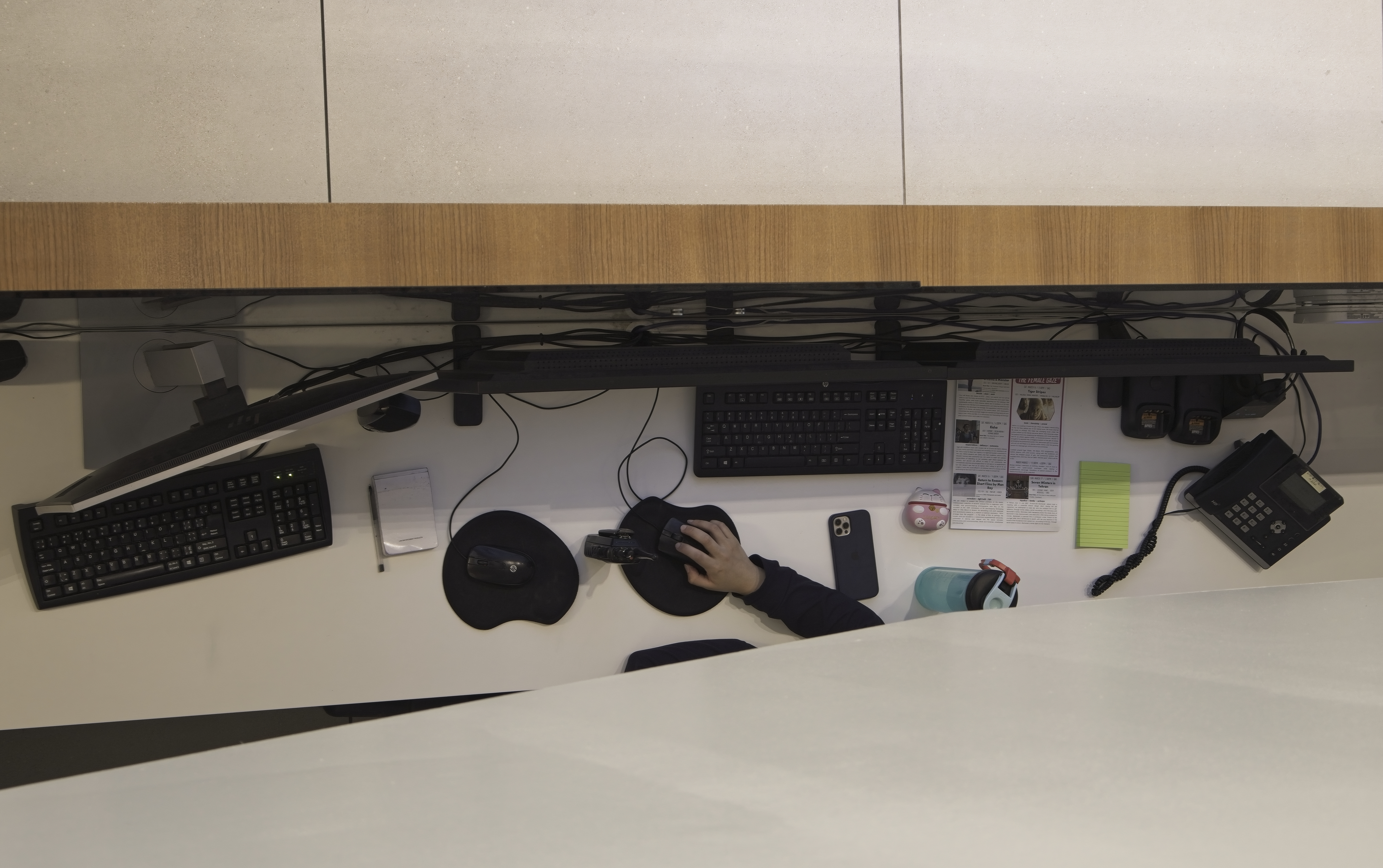 a view of a desk work area from above with just a hand on the computer mouse in view