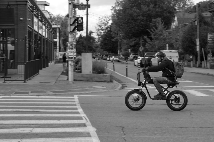 a man on an interesting bicycle streaks through an intersection.
