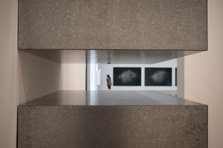 looking through shelves a blurry image of a woman in a gallery