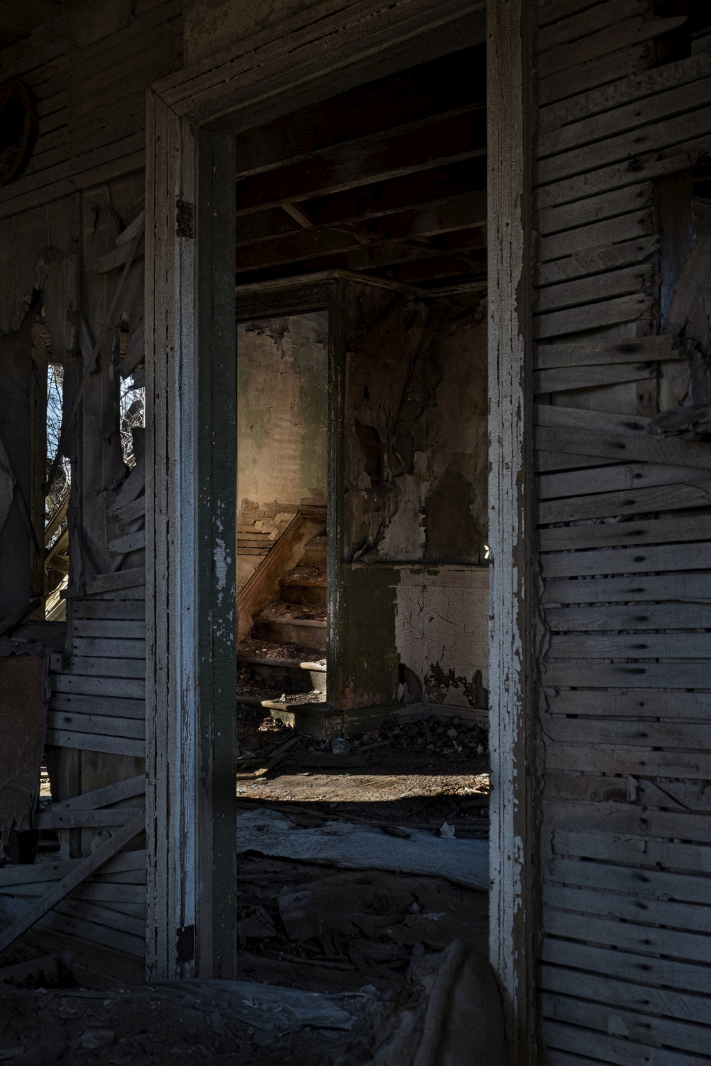 sunlight on the stairs of an old abandoned shack seen through a doorway