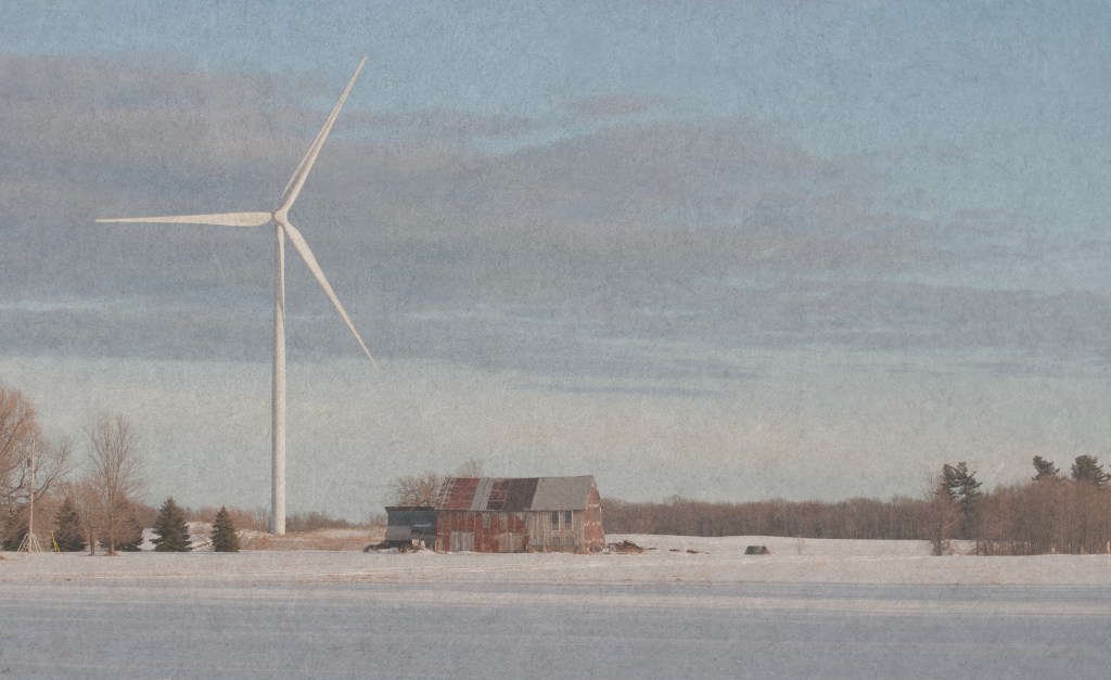 A wind turbine looms over an old barn.